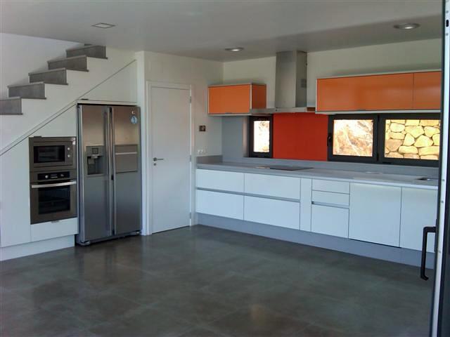 Cocina blanca con toques en colores y aprovechamiento del bajo de escalera