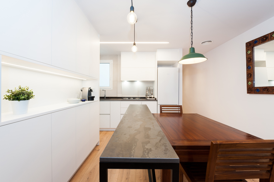 Cocina en Forma de L y con isla compuesta por una barra de hierro y mesa de madera