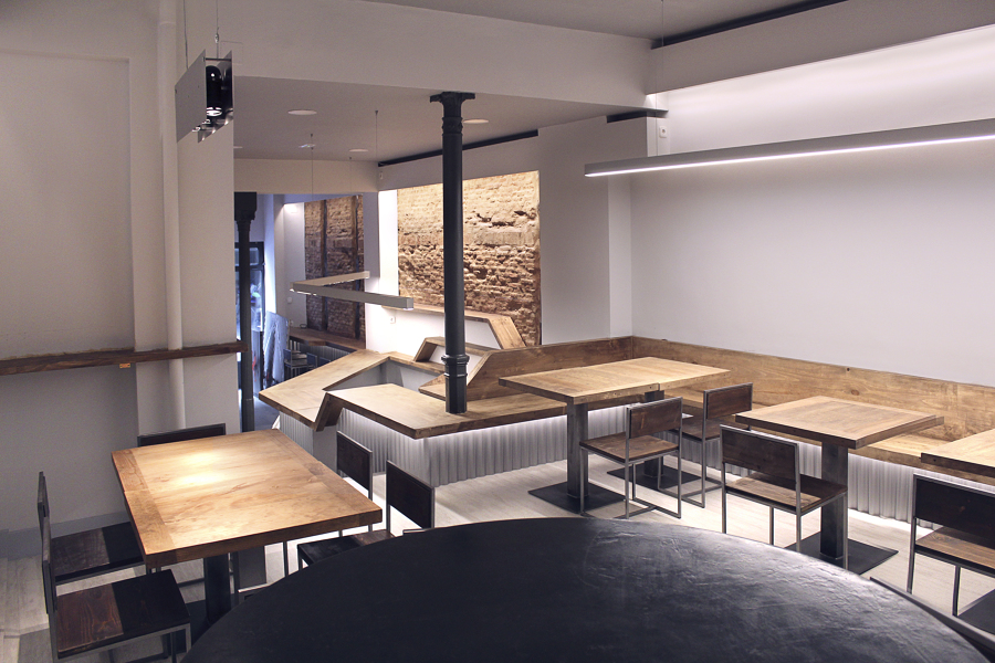 Zona comedor donde la barra se transforma en banco e iluminación ambiental