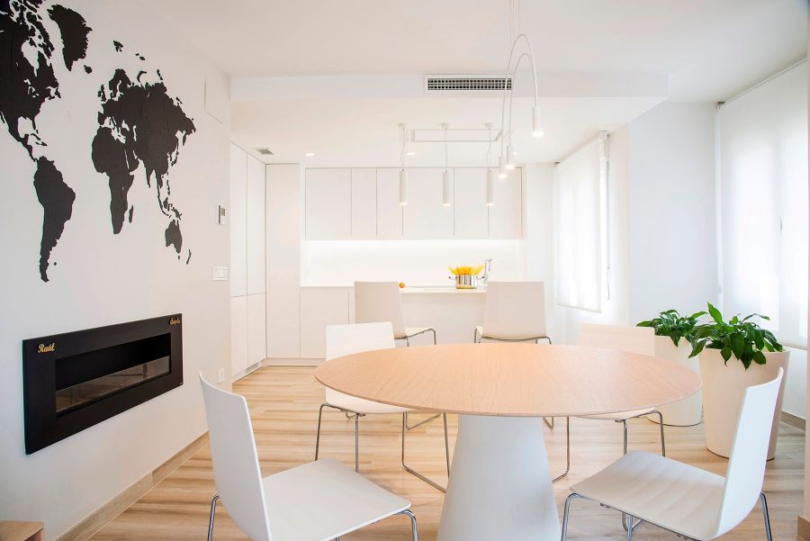 Comedor moderno con mesa redonda y cocina al fondo con isla al fondo.