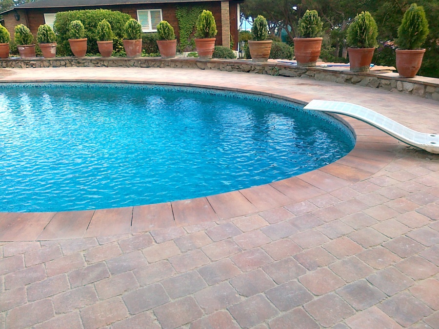 Coronación piscina mediante losa mismo color al adoquín