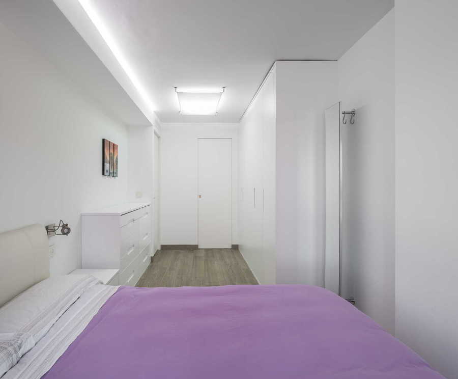 Dormitorio de color blanco con edredón malva