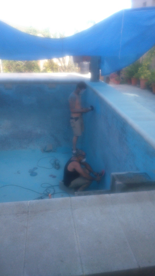 Dos operarios quitando con radial pequeña