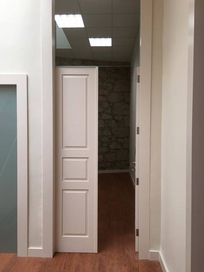 Entrada a oficina con pared de canto tratada al fondo