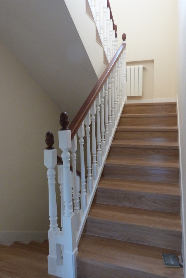 Escalera forrada con cerámica y barandilla bicolor.