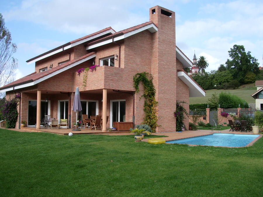 Fachada de ladrillo visto, jardín y piscina
