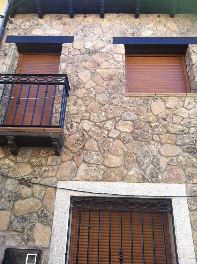 fachada de piedras con cornisa de hormigon imitacion madera