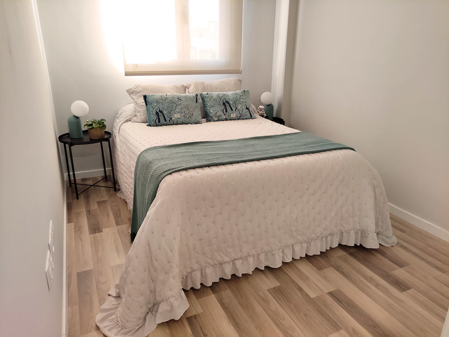 Habitación principal decorada en tonos blancos, dorados y turquesas.