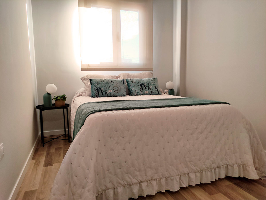 Habitación principal decorada en tonos blancos, dorados y turquesas.