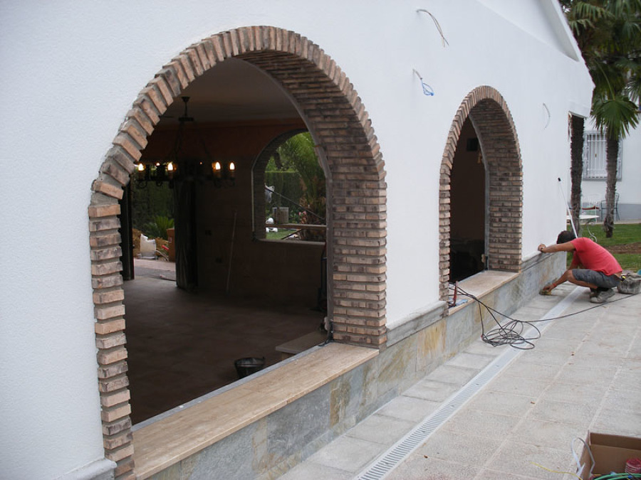 Lateral de la fachada compuesta de dos ventanas con arcos de ladrillo viejo.
