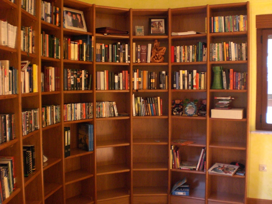 Librería semicircular en madera de Cerezo, con libros.