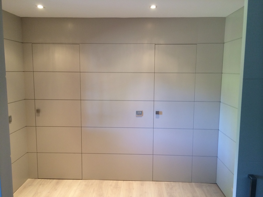 Panelado de la entrada en madera lacada con entrecalles y puertas disimuladas