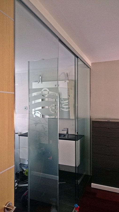 Pared divisoria  ,con paneles y Puerta corredera  de Crista Securit del baño y la habitación  .