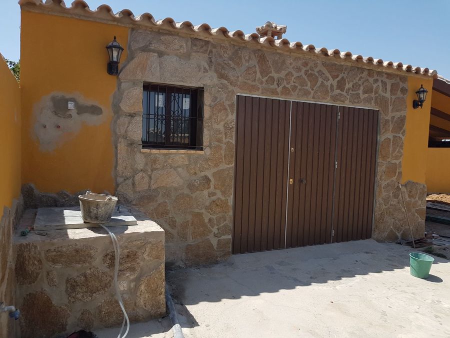 paredes forradas de piedra y puerta de garaje hecha a medida