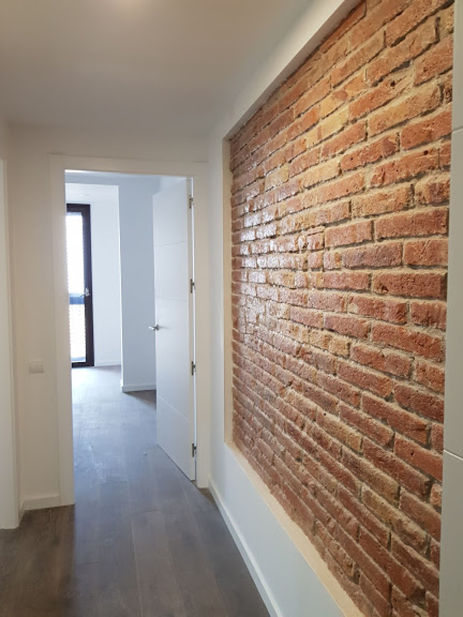 Pasillo terminado con pared original vista y superficies terminadas.