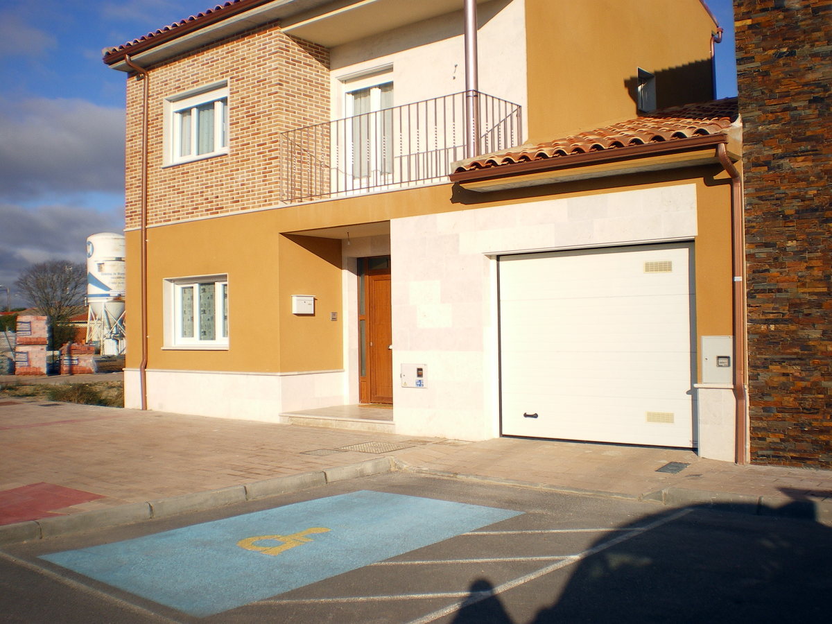 Puerta de entrada en pvc color madera, ventanas en PVC blanco, y puerta de garaje 