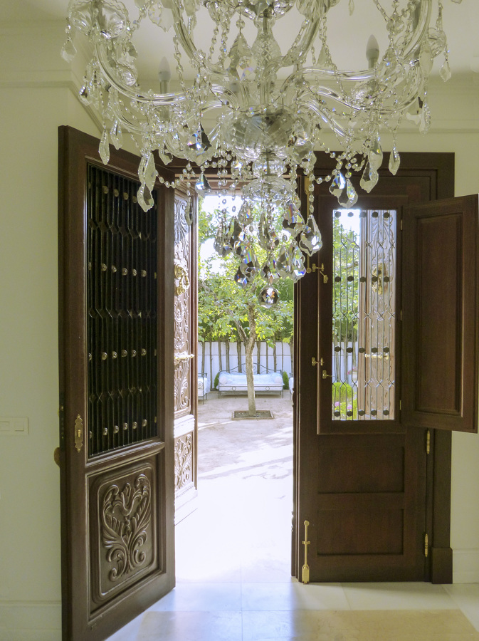 Puerta de madera con ventanas y rejas de forja con detalles dorados