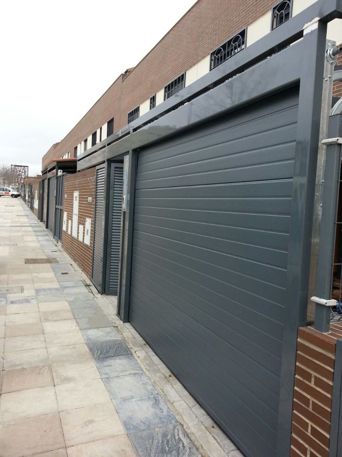 Puerta seccional con peatonal al lado integrado en estructura de techo de cristal