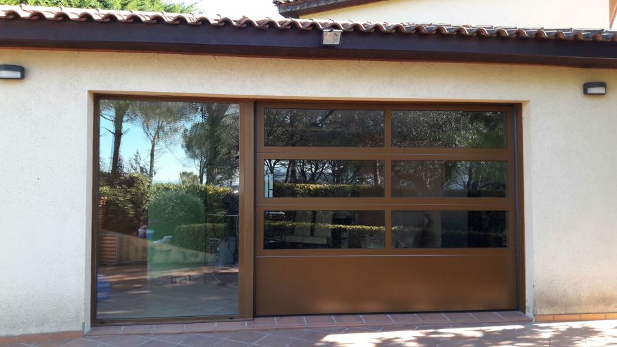 Puerta seccional con perfileria de aluminio y doble vidrio con fijo adosado. www.puertasmaemar.es