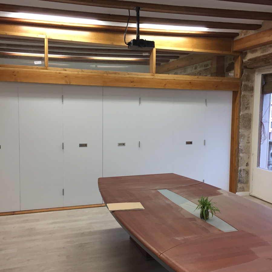 PUERTAS PLEGABLES EN AULA CON PAREDES Y VIGAS RÚSTICAS.