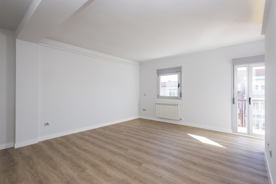 Salón moderno con iluminación LED en el techo, abierto a la cocina y con balcón