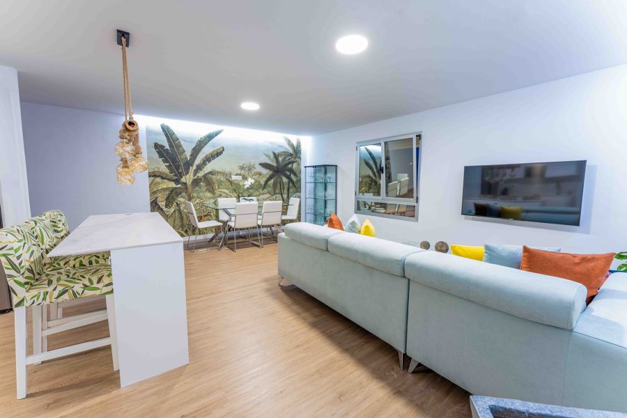 Salón moderno con fotomural junto al comedor y luces LED