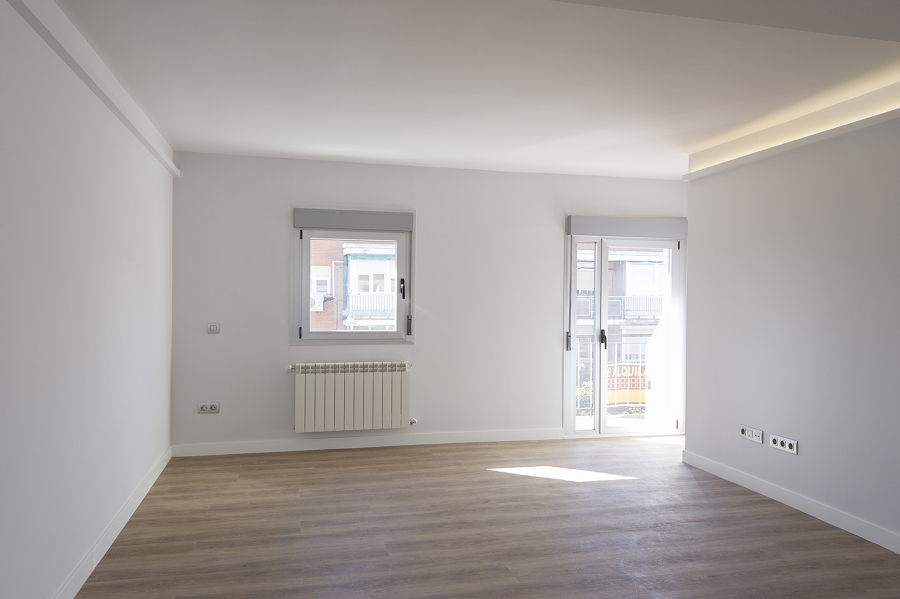 Salón moderno con iluminación LED en el techo, abierto a la cocina y con balcón