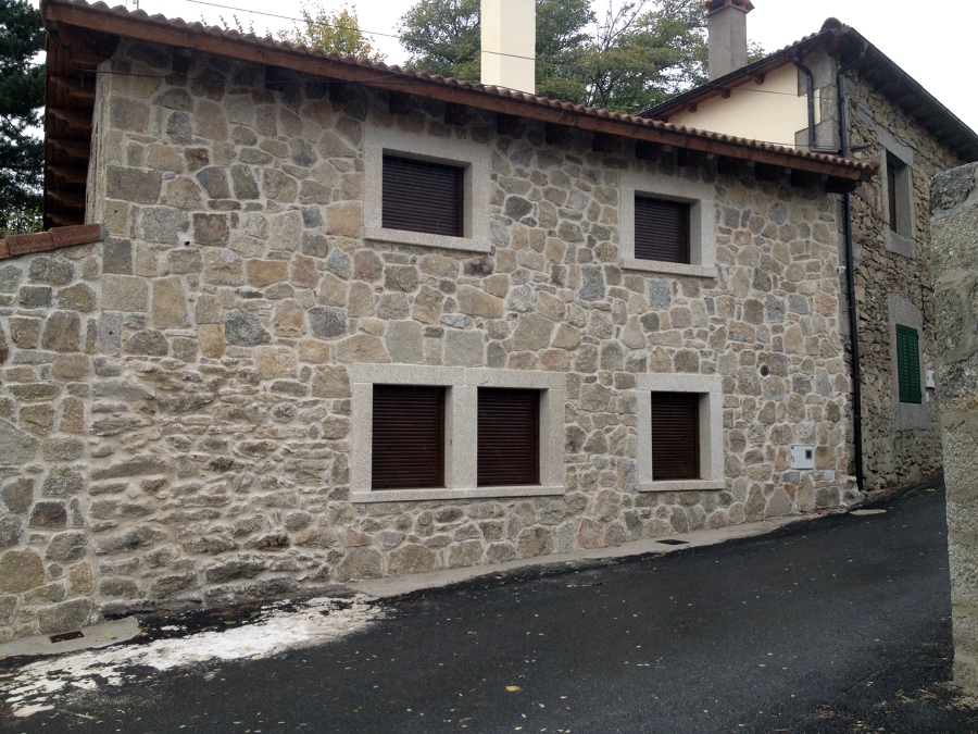 Ventanas con persiana en fachada de piedra