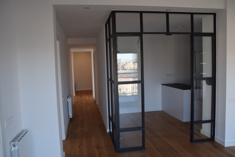 Vista del pasillo desde el comedor con la cocina en espacio semi-abierto.