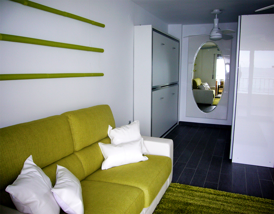 Zona del sofá en primer plano. Literas y zona vestidor al fondo