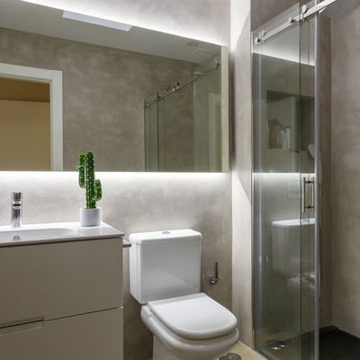 Baño revestido con microcemento y azulejo tipo madera en el suelo.