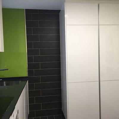 Combinación de texturas en pared, ocultando nevera y dando un amplio servicio de despensa.