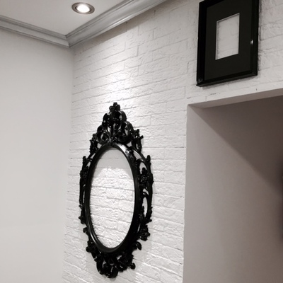 Detalle pared revestida de ladrillo "rústico", con marcos fotos colgados de ella