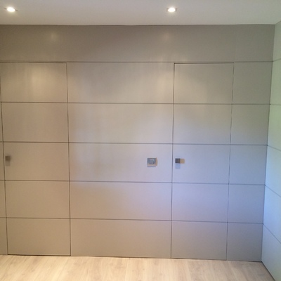 Panelado de la entrada en madera lacada con entrecalles y puertas disimuladas