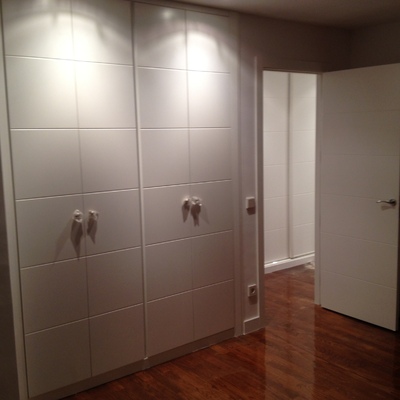 Parquet de tabla ancha teñida en color cerezo que contrasta con la carpinteria lacada en blanco