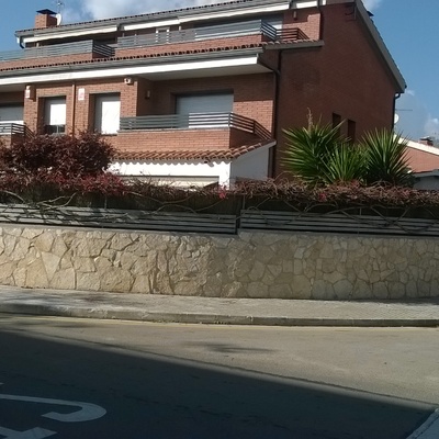 Colocación de piedra natural en un  muro perimetral cara exterior del frente de casa adosada en Barcelona