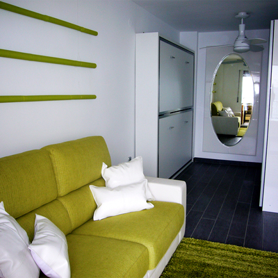 Zona del sofá en primer plano. Literas y zona vestidor al fondo