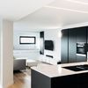 Cocina moderna abierta con frentes negros y encimera blanca