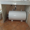 Termo de 100L colocado bajo lavabo en cuarto de baño principal de modo horizontal.